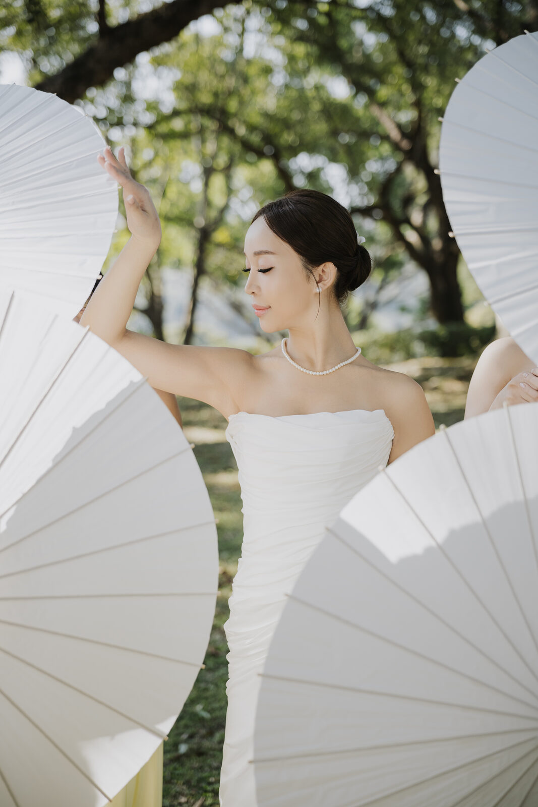 Bride posing with paper parasols in golden light